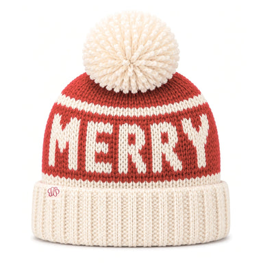 A festive knit beanie hat featuring a red upper section with 'MERRY' knitted in cream, a cream pom-pom on top, and a cream ribbed cuff. A small red monogram logo is visible on the cuff.