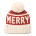 A festive knit beanie hat featuring a red upper section with 'MERRY' knitted in cream, a cream pom-pom on top, and a cream ribbed cuff. A small red monogram logo is visible on the cuff.