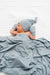 Newborn baby wrapped in a blue blanket and wearing a matching blue hat on a white background