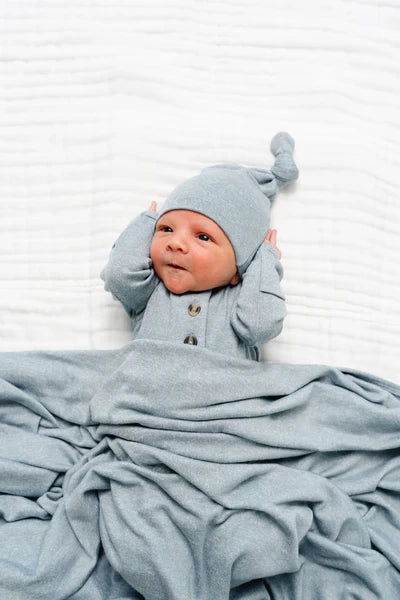 Newborn baby wrapped in a light blue blanket and wearing a matching hat on a white background