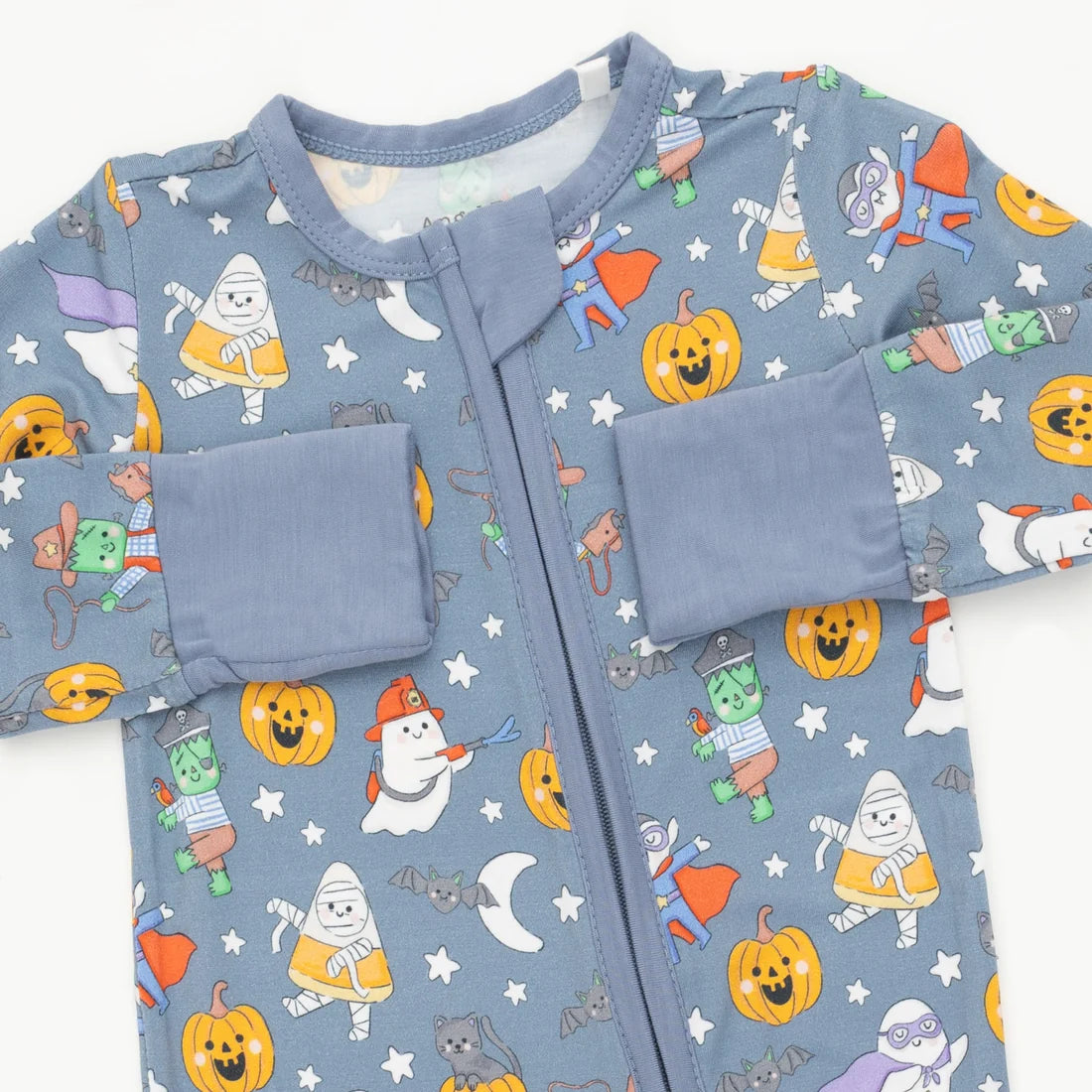 A baby long-sleeve zip-up sleeper in dusty blue with a colorful Halloween print featuring pumpkins, ghosts, candy corn, bats, and stars, shown flat on a white background.