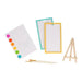 Art supplies including a color chart, small easel, and paintbrushes on a white background
