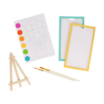 Artistic tools including a small easel, paintbrush, color chart, and blank paper on a white background.