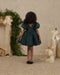 Young girl wearing a dark green shimmer dress with puff sleeves and a full skirt in a festive room Noralee holiday clothing collection