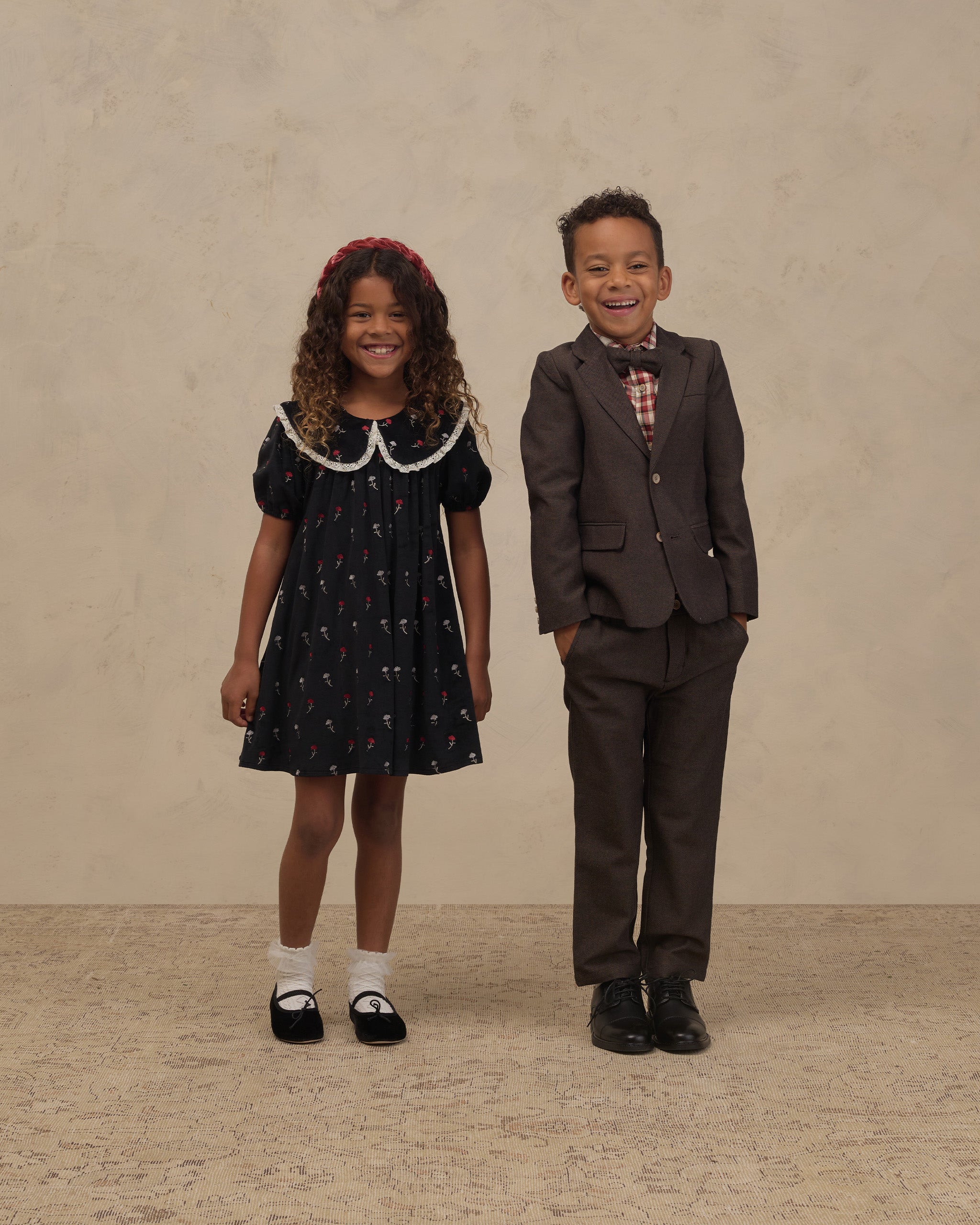 Girl wearing a black floral dress with a white lace collar and puff sleeves beside a boy in a brown suit Noralee Janette Dress Winter Ditsy
