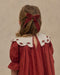 Child seen from behind wearing a ruby red dress with embroidered scalloped collar and puff sleeves with a matching velvet bow in her hair by Noralee