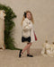 Noralee cream faux fur coat on a young girl with a full collar and hidden front snaps styled with a black bow purse and Mary Jane shoes in a festive room