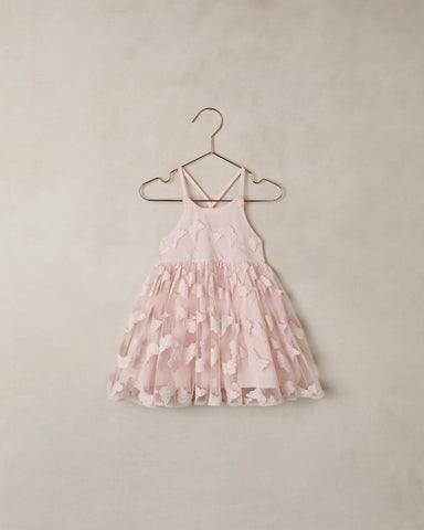 Pink floral dress on a hanger against a beige wall