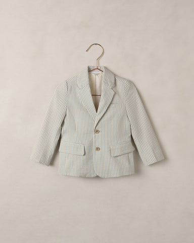 Blue and white striped blazer on a hanger against a beige background
