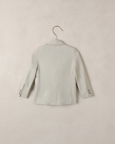 Blue and white striped shirt on a hanger against a beige background