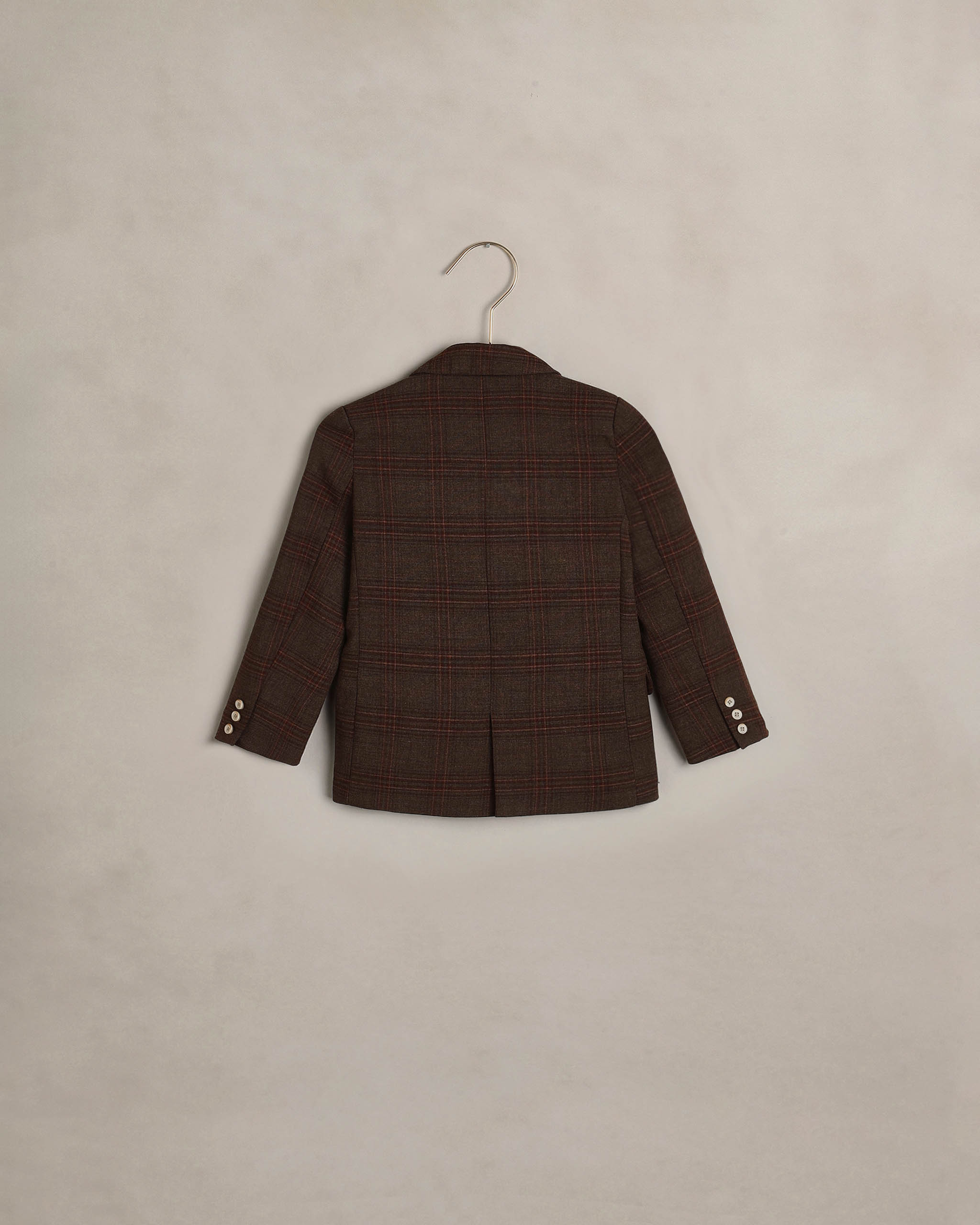 Back view of a boys heathered plaid blazer by Noralee with a center vent and buttoned cuffs displayed on a hanger