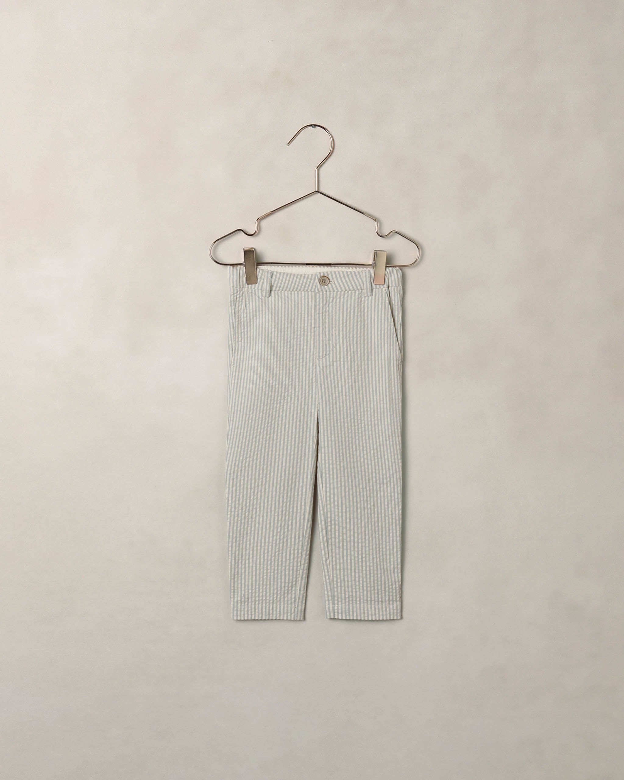 Striped pants on a hanger against a beige background