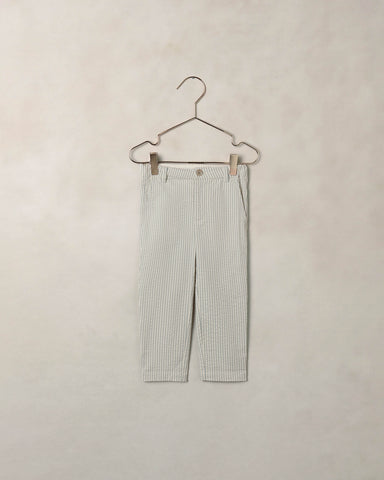 Striped pants on a hanger against a beige background