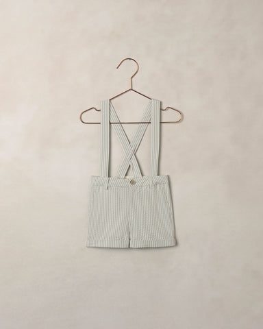 Striped shorts with suspenders on a hanger against a beige background