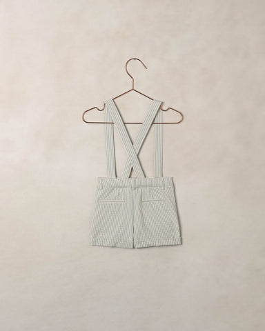 Green checkered dress with suspenders on a beige background