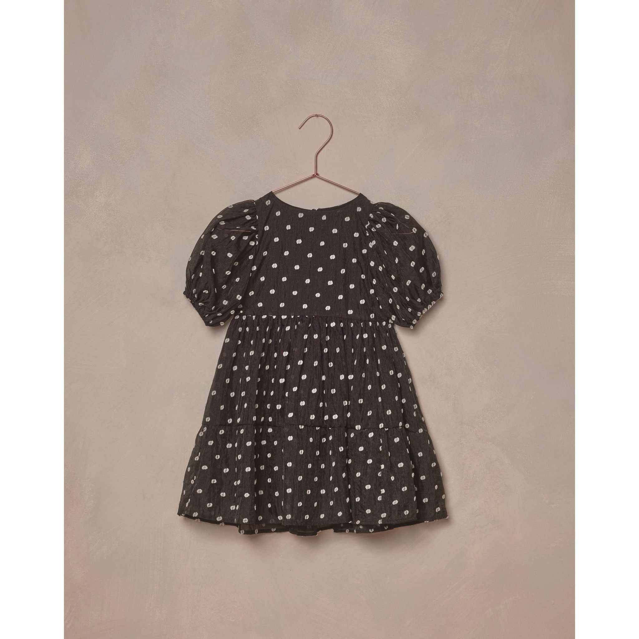 black midi dress with layered tiered skirt, full puffed sleeves, and a delicate button-back closure and white polka dots
