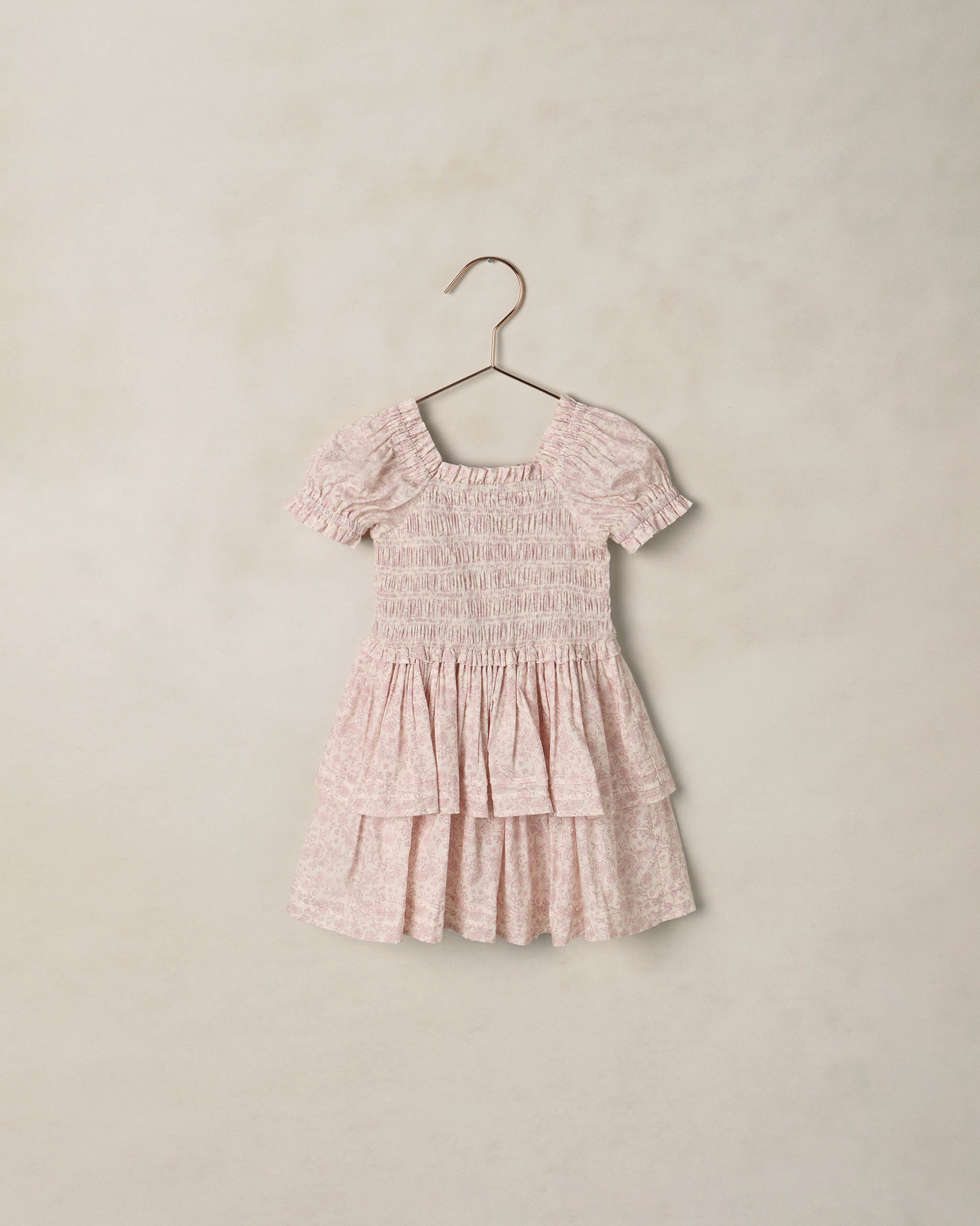 Lavender floral dress on a hanger against a beige background