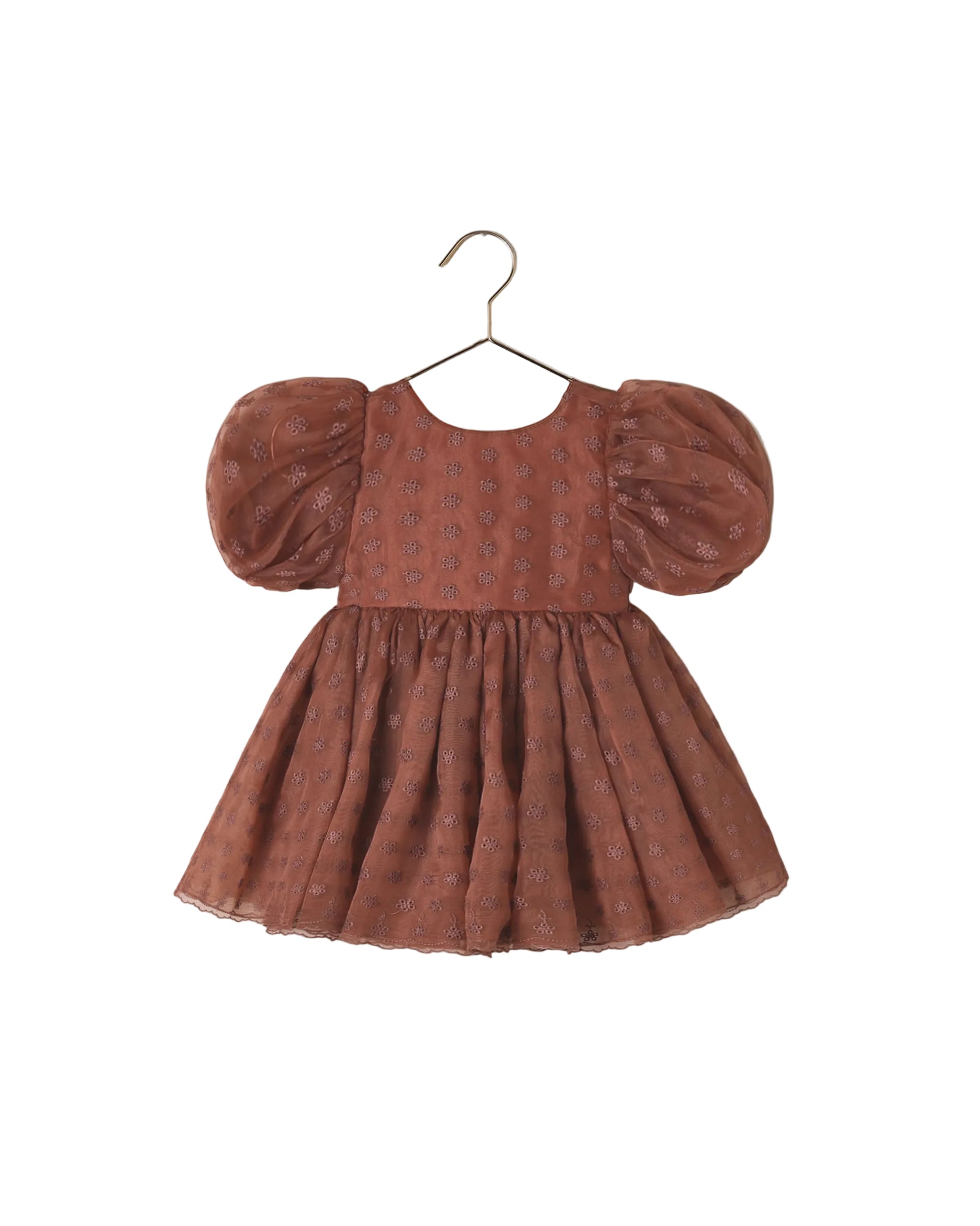 A toddler girl's terracotta-colored dress with puff sleeves and a subtle floral pattern, hanging on a metal hanger against a white background.