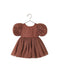 A toddler girl's terracotta-colored dress with puff sleeves and a subtle floral pattern, hanging on a metal hanger against a white background.