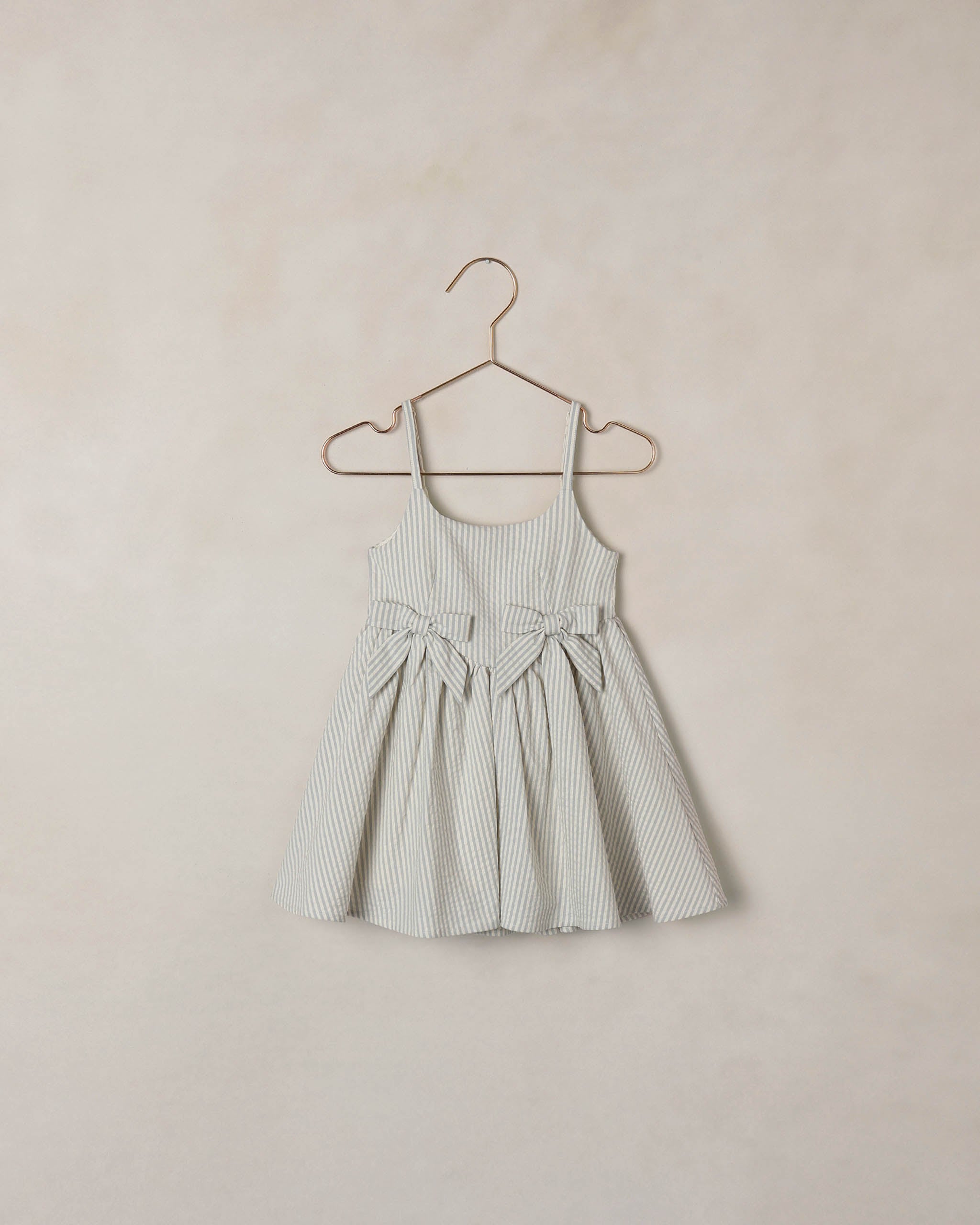 Striped dress on a hanger against a beige wall