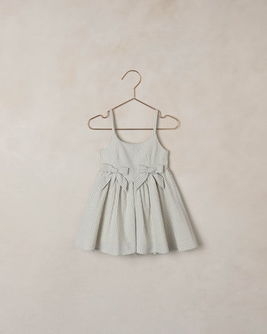 Striped dress on a hanger against a beige wall