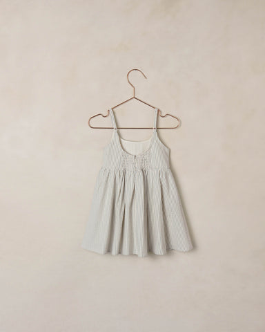 Striped dress on a hanger against a beige wall