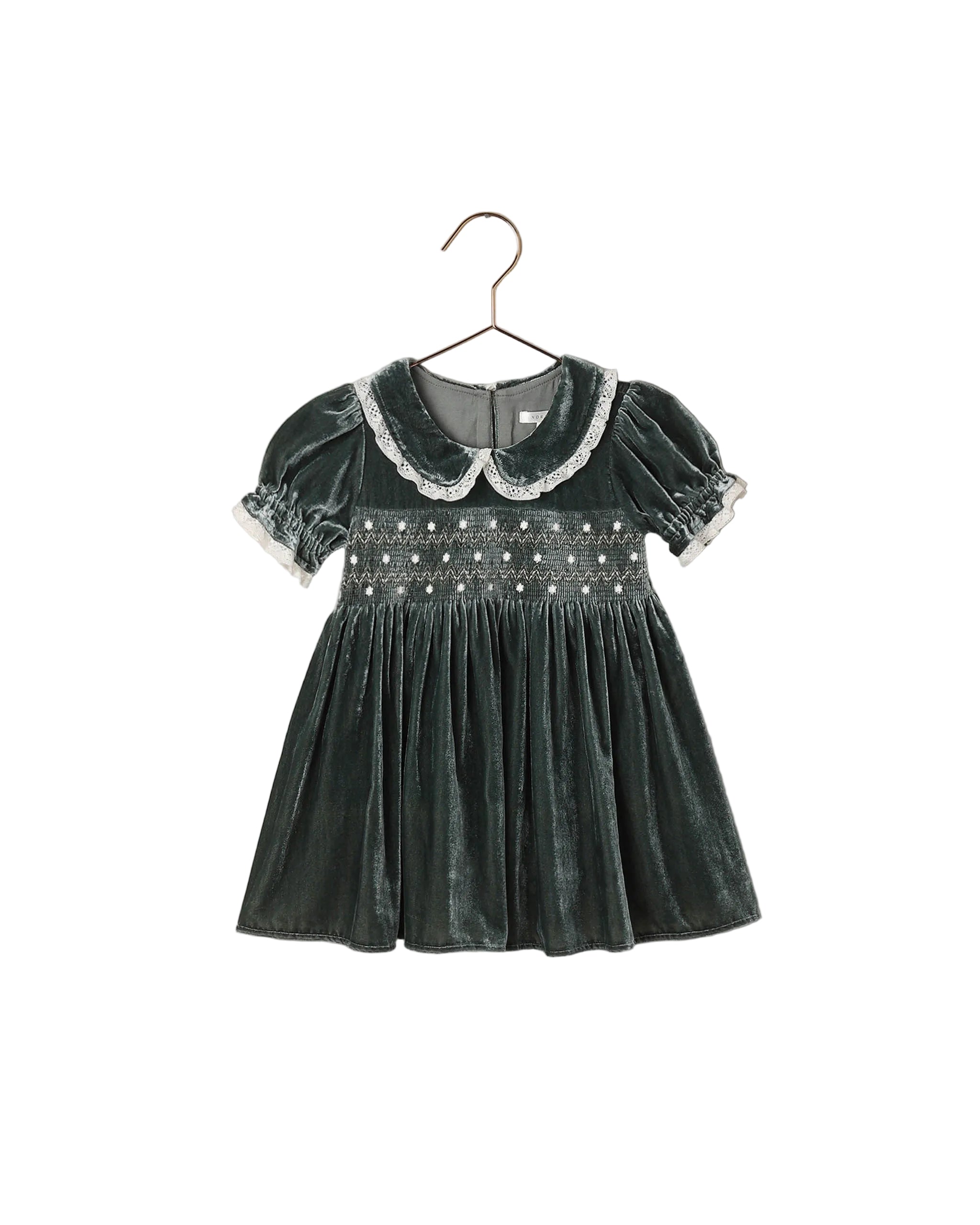 A green velvet dress featuring a smocked bodice, puff sleeves with lace trim, and a scalloped lace Peter Pan collar.