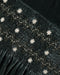 A close up of a green velvet fabric with a delicate embroidered detail.