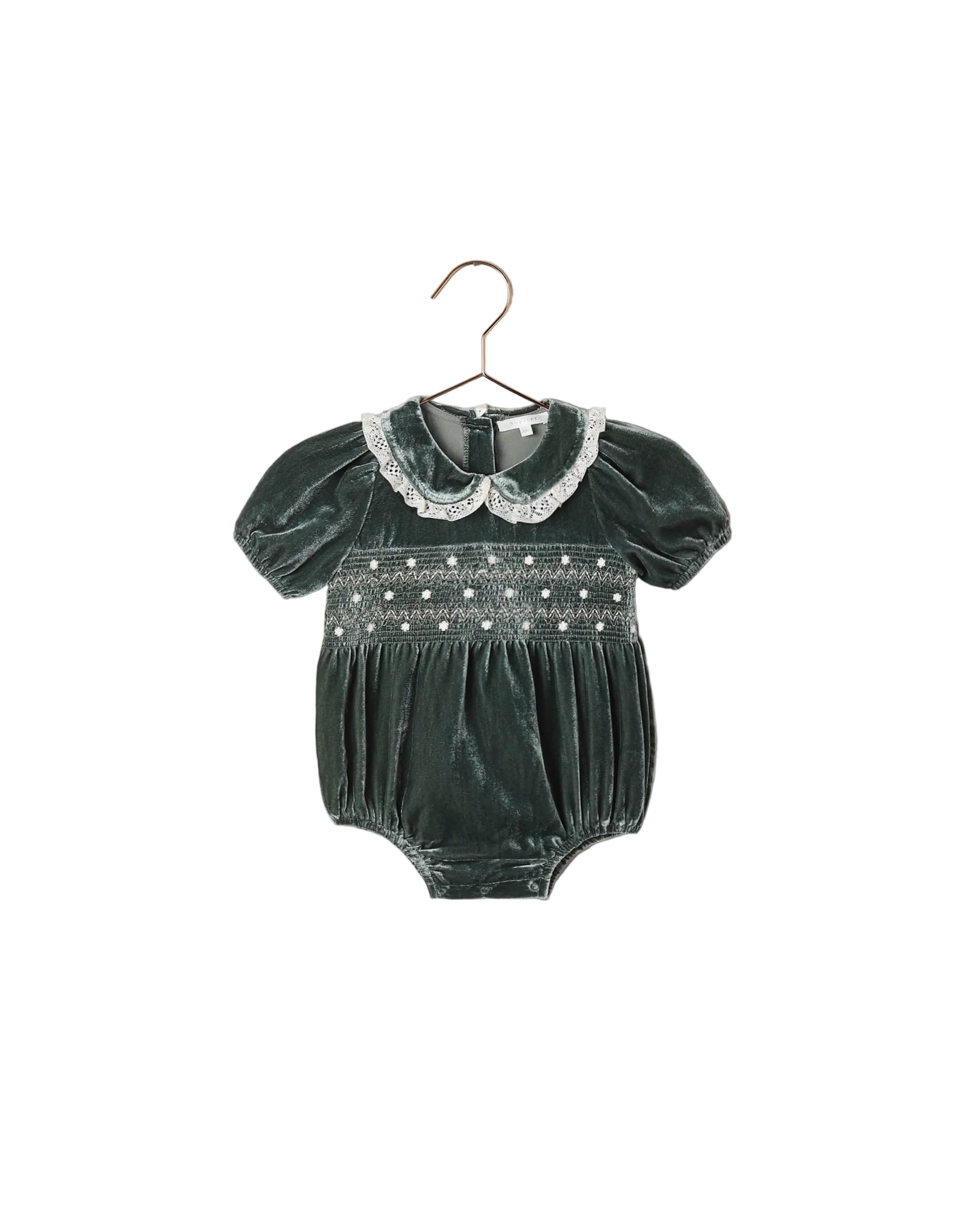 A green velvet romper with a smocked bodice, delicate embroidered details, puff sleeves, and a scalloped lace Peter Pan collar. 