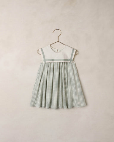 Green checkered dress on a hanger against a beige background