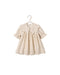 A cream-colored baby dress with a large ruffled Peter Pan collar, short flutter sleeves, and delicate eyelet embroidery, hanging on a wooden hanger against a white backgroundl.