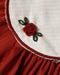 Close up of a Noralee ruby red dress with a cream scalloped collar red trim and delicate embroidered rose detail above the pleated skirt