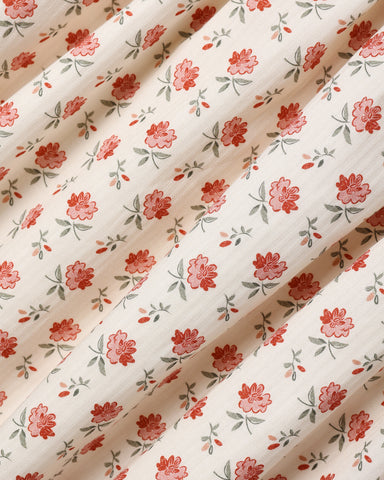 A close up of an ivory fabric with a floral pattern.