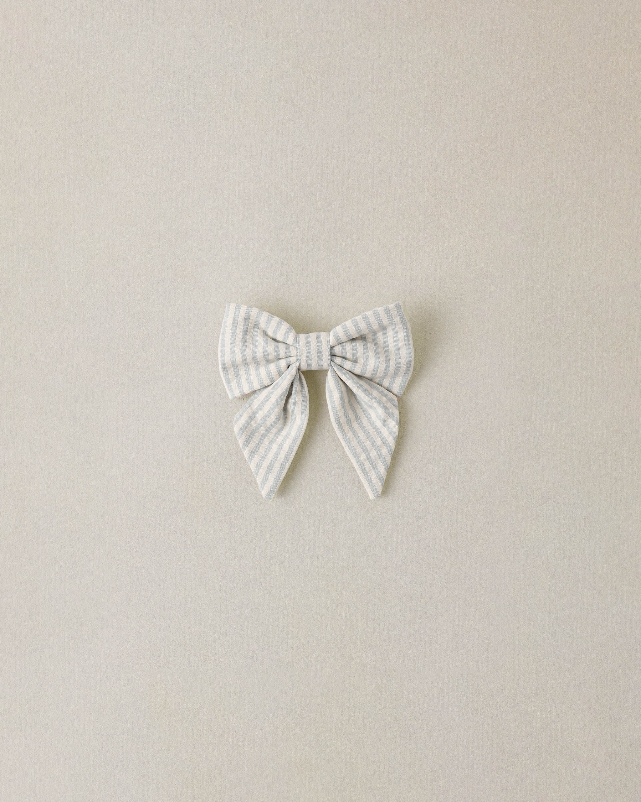 Striped bow hair accessory on a beige background