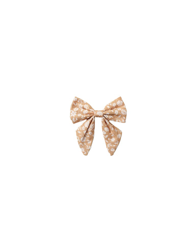 A small fabric bow accessory with a beige and white floral pattern, centered on a plain white background.