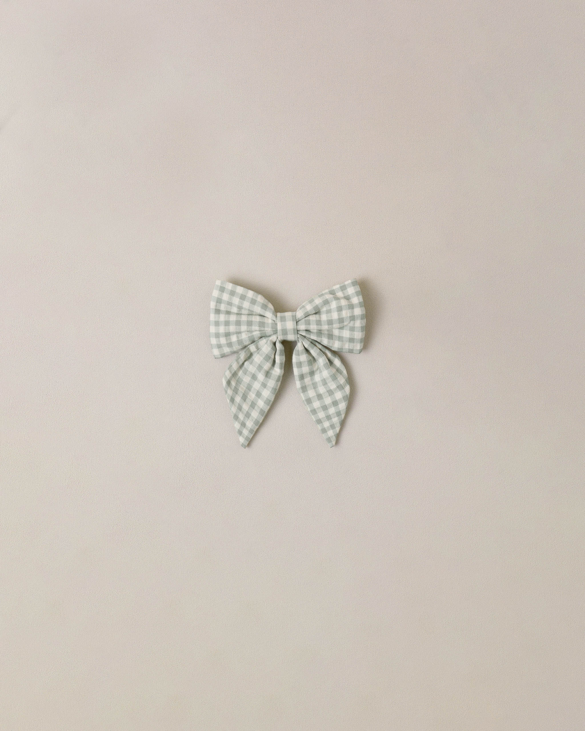 Green and white checkered bow on a beige background