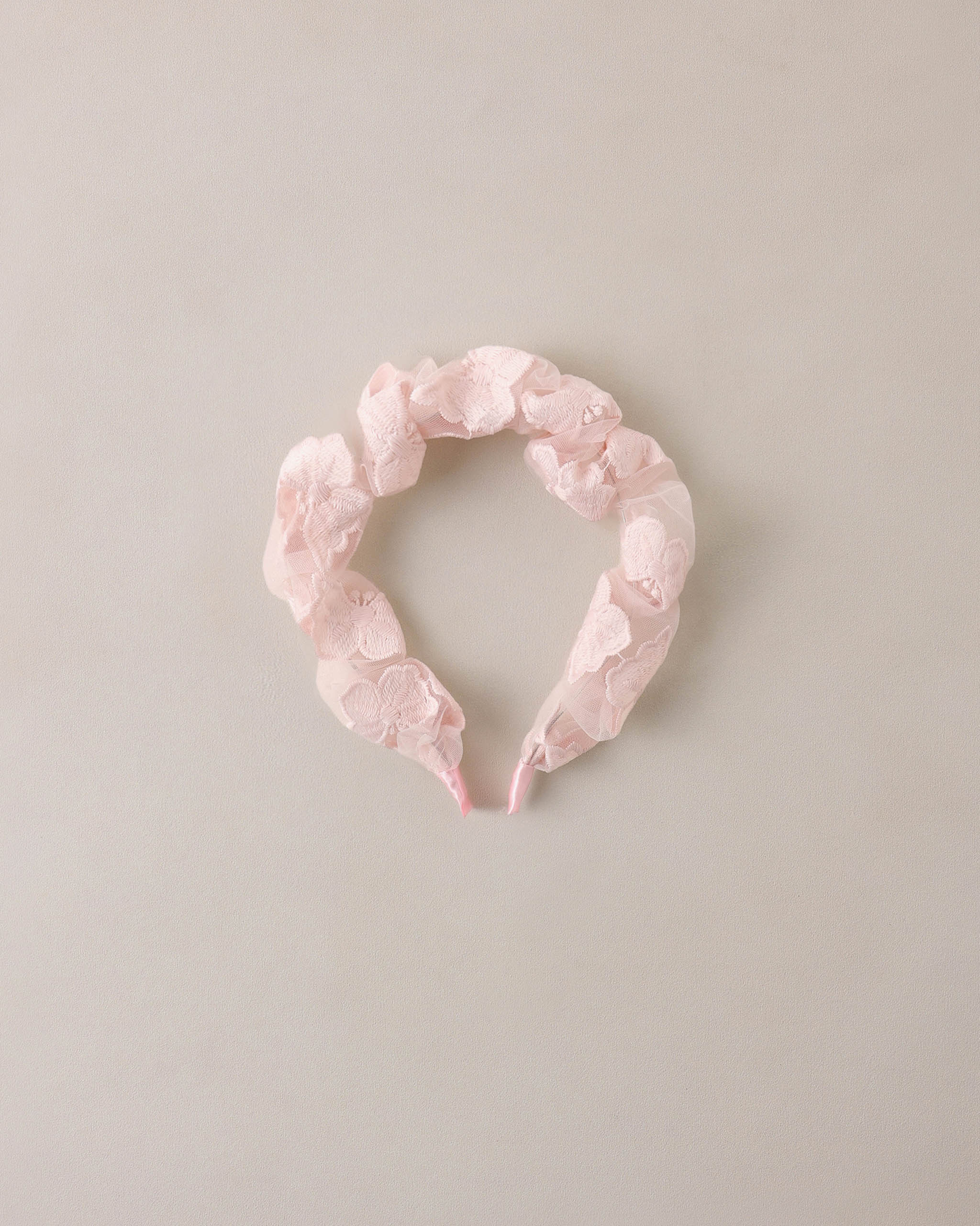 Pink floral headband on a light beige background