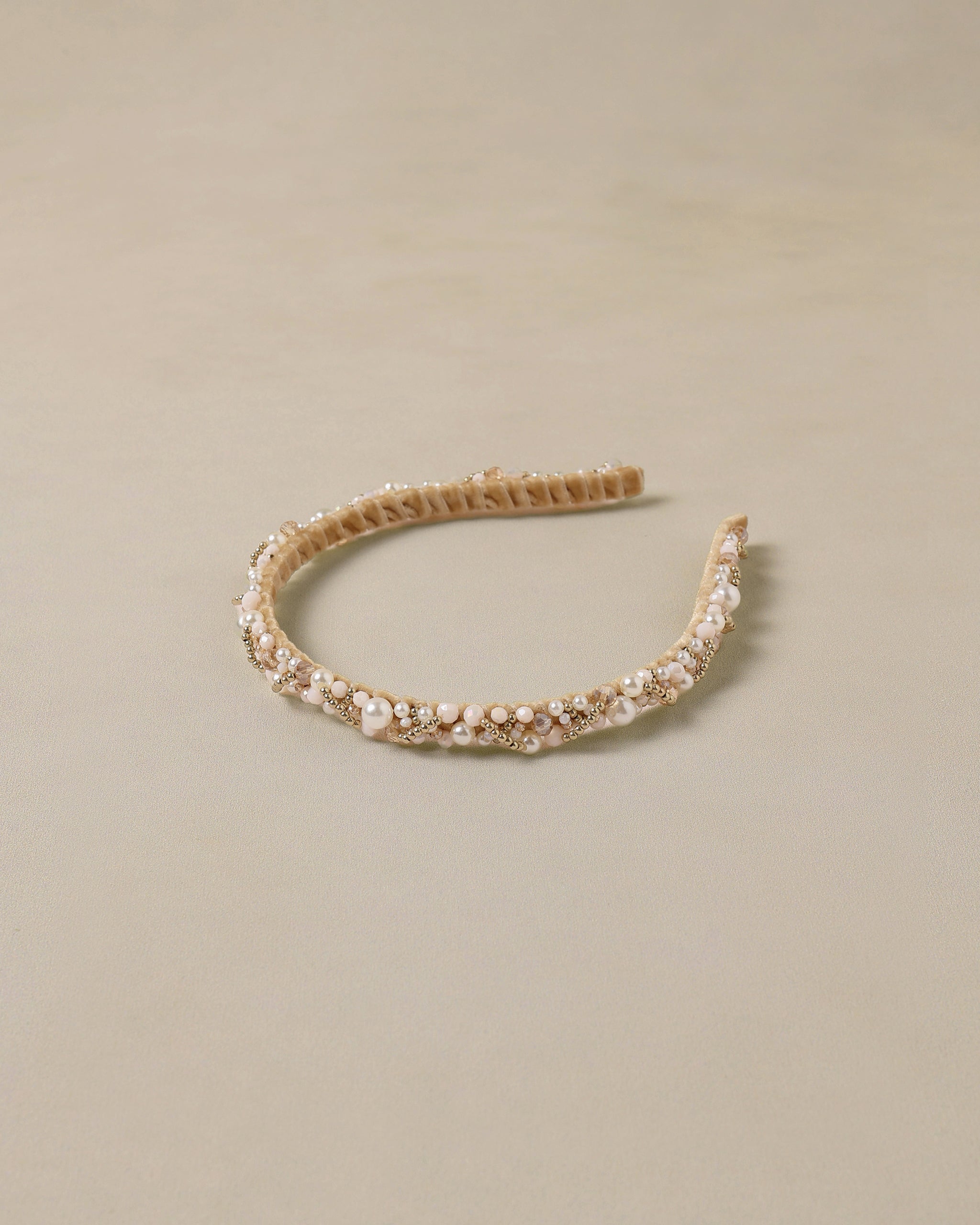 Gold headband with pearls on a beige background