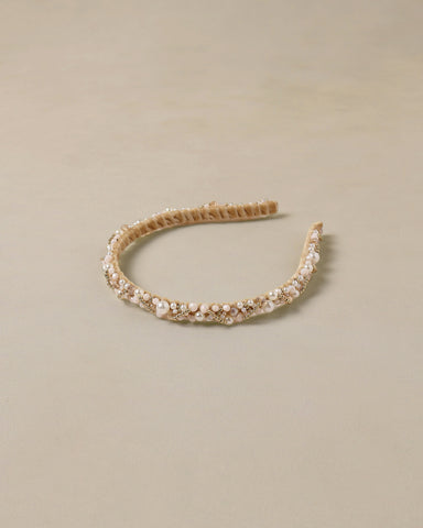 Gold headband with pearls on a beige background