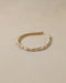 Gold headband with pearls on a beige background