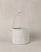 Textured blue and white striped basket with handle on a beige background