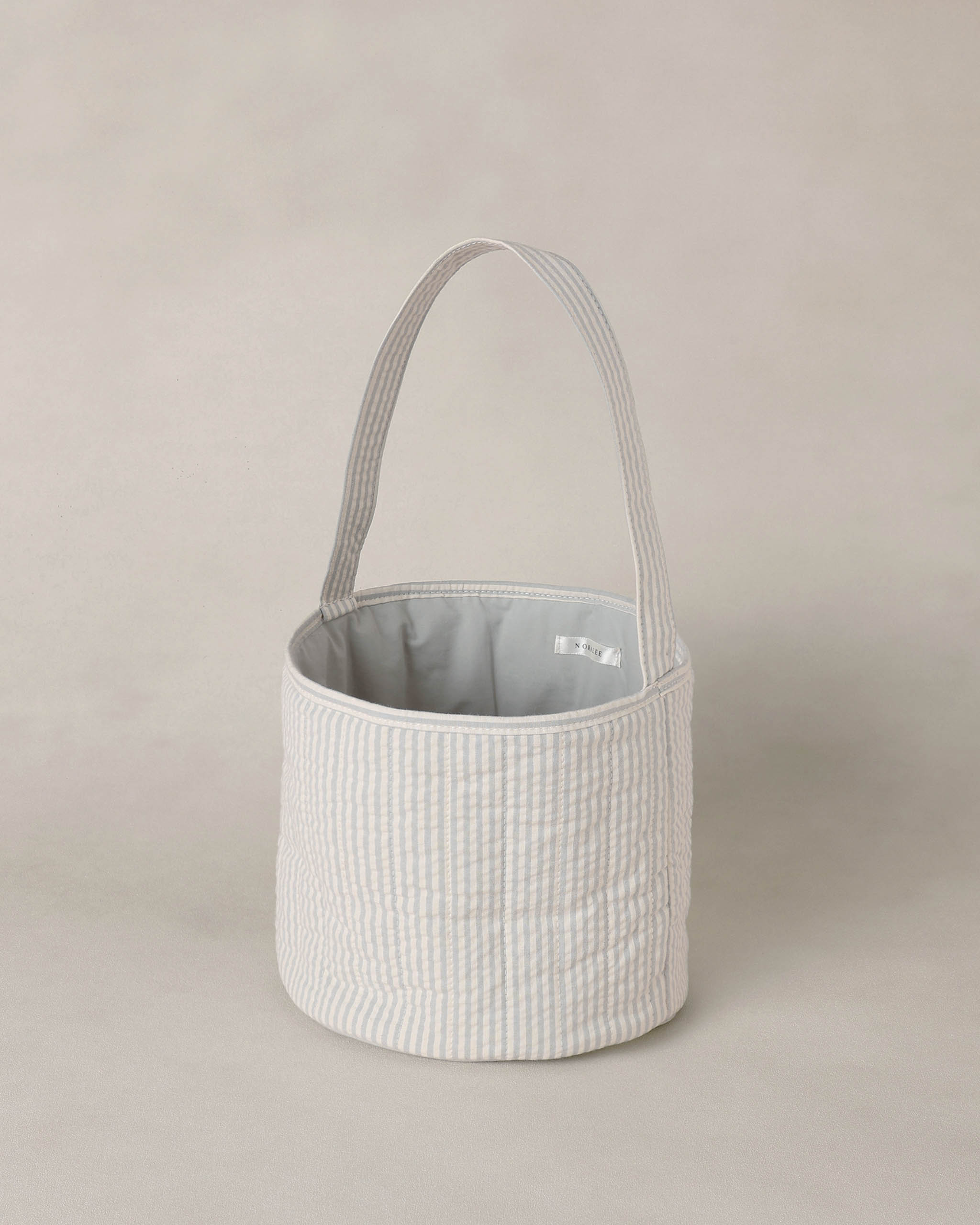 Textured blue and white basket with handle on a beige background