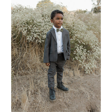boy wearing pine green colored velvet bow tie with white dress shirt and charcoal suit