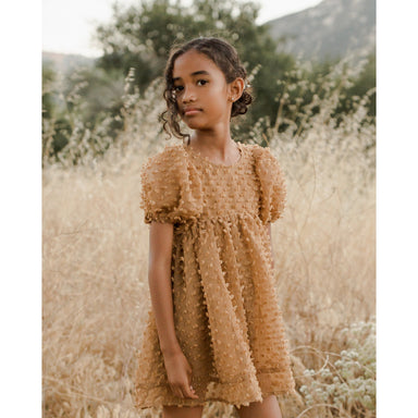 girl wearing gold colored babydoll style dress with popcorn fabric and puff sleeves