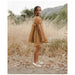 girl wearing gold colored babydoll style dress with popcorn fabric and puff sleeves with gold ballet flats