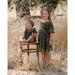 baby girl sitting up wearing pine green colored long sleeve velvet bubble with ruffle detail at the neck and gathered waistline posing with girl wearing matching dress