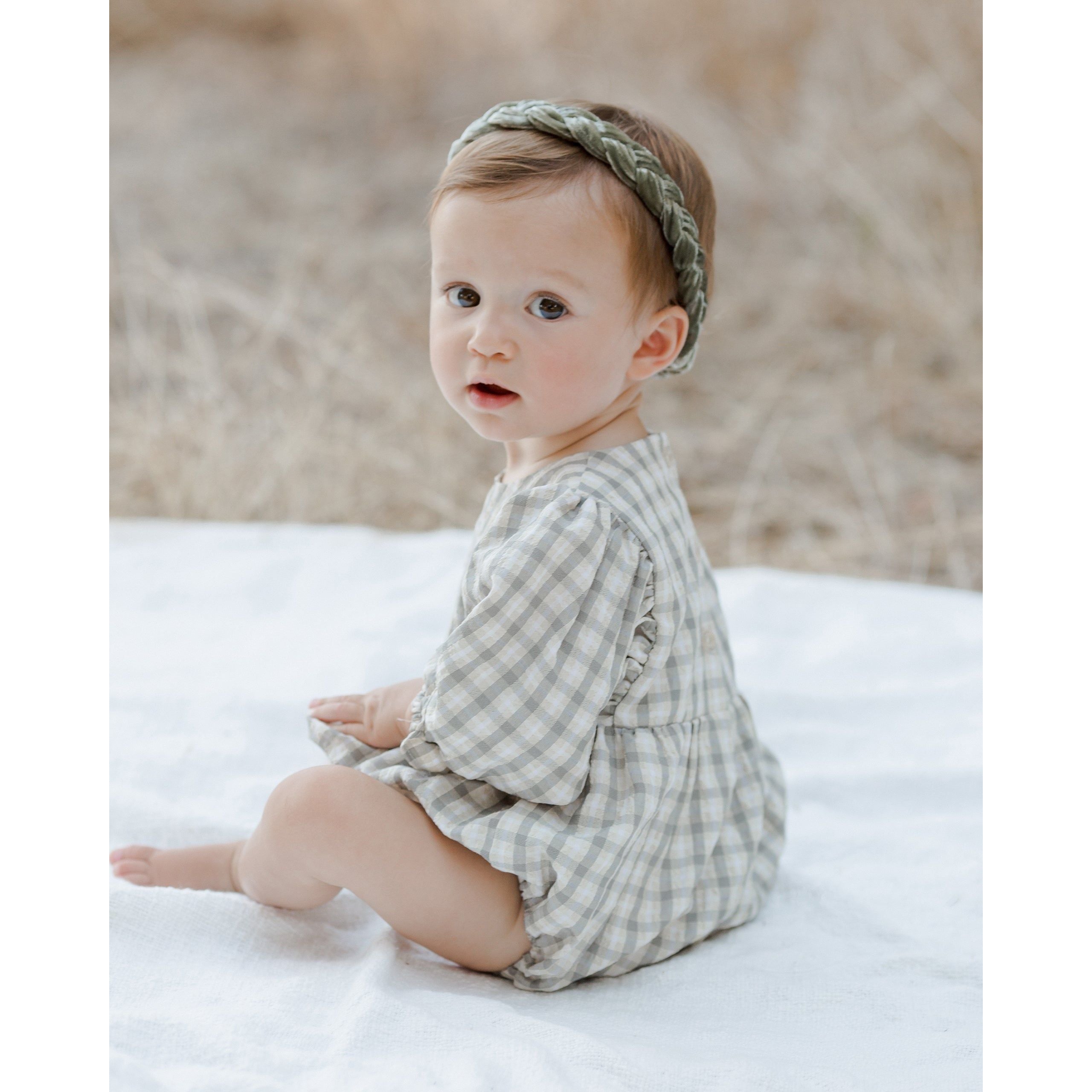 back view of baby girl wearing baby girl sitting wearing ivory long sleeve bubble with gathering at the waist and wrists with green plaid print