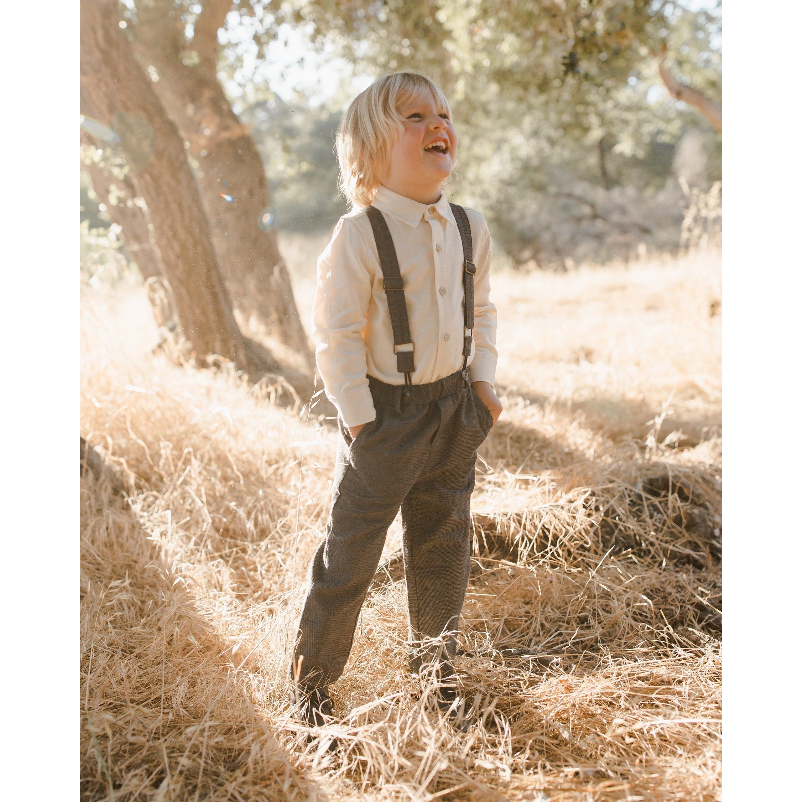 boy wearing boy wearing charcoal black suspender pants with white button down dress shirt