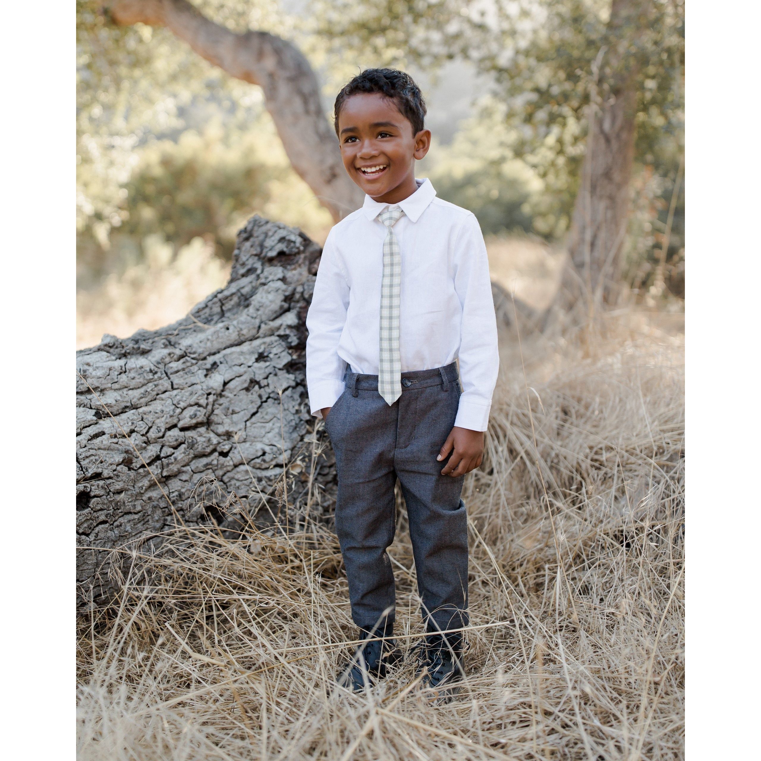 boy wearing boy wearing olive green and ivory plaid skinny tie with white dress shirt and charcoal pants