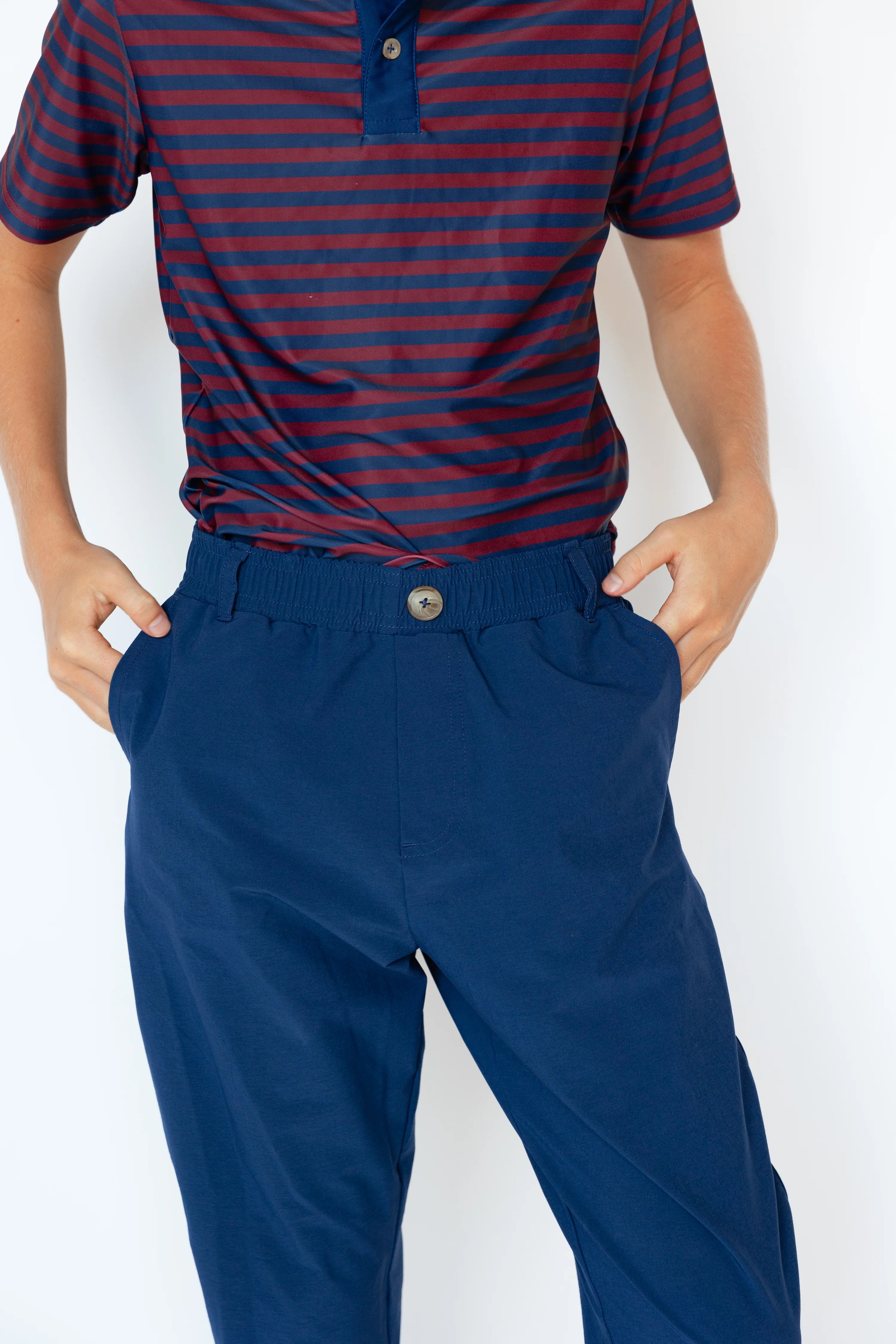 Person wearing a red and blue striped shirt with blue joggers on a white background
